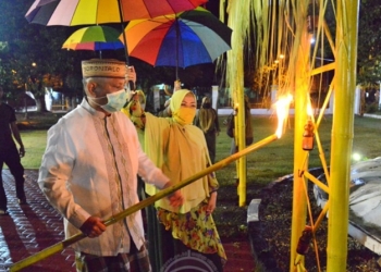 Gubernur Gorontalo Rusli Habibie bersama istri Idah Syahidah menyalakan lampu botol yang sudah terpasang di gerbang adat atau alikusu, Selasa (19/5/2020). Penyalaan lampu botol sebagai bagian dari tradisi malam tumbilatohe atau pasang lampu tiga hari jelang hari raya Idulfitri. (Foto: Salman-Humas).