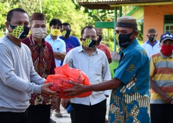 Sekretaris Daerah, Ridwan Yasin saat menyalurkan sembako kepada 100 warga penerima bantuan yang berada di Kecamatan Biau, Kabupaten Goronto. (foto.istimewa)