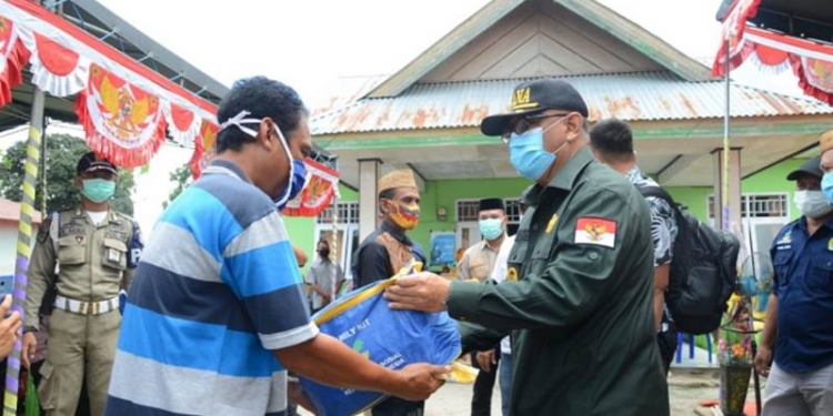 Gubernur Gorontalo Rusli Habibie (kanan) menyerahkan bantuan kepada salah satu korban kebakaran rumah di Kabupaten Boalemo, Sabtu (26/9/2020). Ada tiga KK yang menjadi korban kebakaran selang waktu Juli hingga September yang tersebar di tiga desa yakni Dulohupa, Dimito dan Rumbia. (Foto: Alfred-Humas).