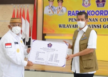 Kepala BNPB Letjen TNI Doni Monarno (kanan) menyerahkan secara simbolis bantuan penanganan covid-19 kepada Gubernur Gorontalo Rusli Habibie, Rabu (7/10/2020). Bantuan ventilator, alat uji swab, APD hingga masker itu diharapkan bisa membantu penanganan covid-19 di daerah. (Foto: Alfred-Humas).