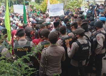 Massa aksi dan petugas Kepolisian saling dorong di depan pintu DPRD Kota Gorontalo dalam aksi unjuk rasa menolak penetapan UU Cipta Kerja, Kamis (8/10/2020). (Isno/gopos)