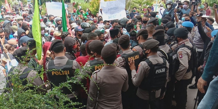 Massa aksi dan petugas Kepolisian saling dorong di depan pintu DPRD Kota Gorontalo dalam aksi unjuk rasa menolak penetapan UU Cipta Kerja, Kamis (8/10/2020). (Isno/gopos)