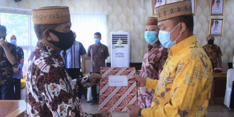 Sekretaris Daerah Provinsi Gorontalo Darda Daraba (kiri) menyerahkan SK Pelaksana tugas  (Plt) Kepala Badan Keuangan Provinsi Gorontalo kepada Danial Ibrahim di ruang Huyula Kantor Gubernur, Jumat (2/10/2020). (Foto: Nova – Humas)