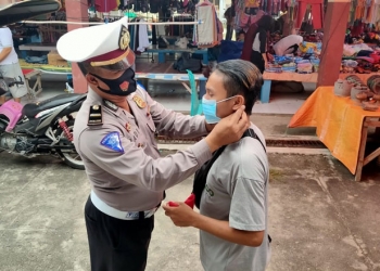 Kasat Lantas Polres Bone Bolango, Iptu A. Wahab Tambipi memasangkan masker kepada warga  dalam pelaksanaan operasi zebra, Selasa (3/11/2020). (Polres Bone Bolango untuk gopos.id)