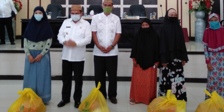 Wali Kota Gorontalo, Marten Taha bersama Ketua Baznas Kota Gorontalo, Marzuki Pakaya, menyerahkan bantuan paket sembako untuk ibu dan janda dhuafa.(sari/gopos)