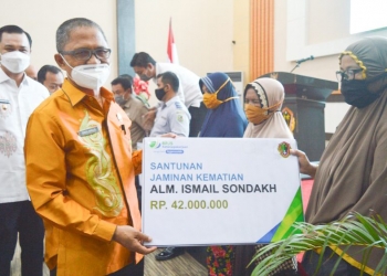 Sekretaris Daerah Kota Gorontalo menyerahkan secara simbolis santunan pekerja yang meninggal dunia, kepada ahli warisnya. Foto: Istimewa.