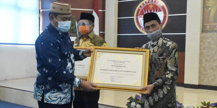Asisten I Setda Provinsi Gorontalo, Syukri J Botutihe, menyerahkan piagam penghargaan Kanwil Kemenkumham Gorontalo kepada Bupati Gorontalo, Nelson Pomalingo, Senin (14/12/2020). (istimewa)