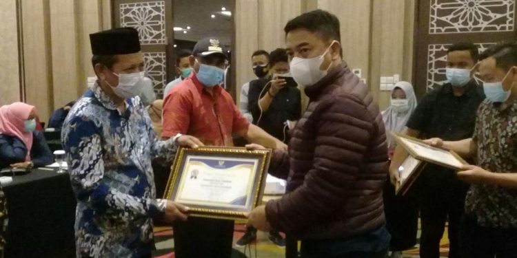 Bupati Hamim Pou, saat memberikan piagam penghargaan kepada 11 desa dengan kinerja pengelolaan keuangan terbaik. Foto: Indra/gopos.