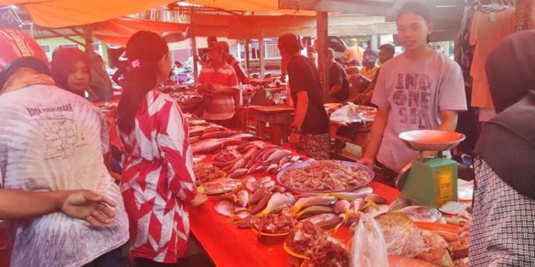 Yahya Matalauni, pedagang ikan dan udang di Pasar mingguan Popayato, Pohuwato saat melayani pengunjung yang hendak membeli ikan tersebut, Selasa (29/12/2020). (ramlan/gopos).