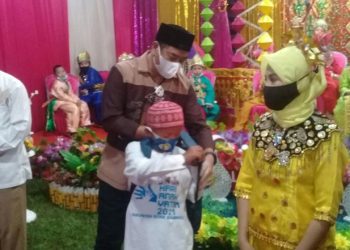 Bupati Bone Bolango, Hamim Pou, menyerahkan bantuan bagi anak yatim pada peringatan Hari Anak Yatim di Bone Bolango, Senin (11/1/2021). (Indra/gopos)