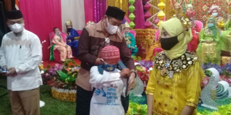 Bupati Bone Bolango, Hamim Pou, menyerahkan bantuan bagi anak yatim pada peringatan Hari Anak Yatim di Bone Bolango, Senin (11/1/2021). (Indra/gopos)