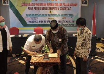 Penandatanganan Perjanjian Kerjasama yang diwakili oleh Kepala Dinas Pemerintah Desa Nawir Tondako Dan General Meneger Bank Sulut Go Cabang Limboto Yusuf Husain. (Putra/Gopos).