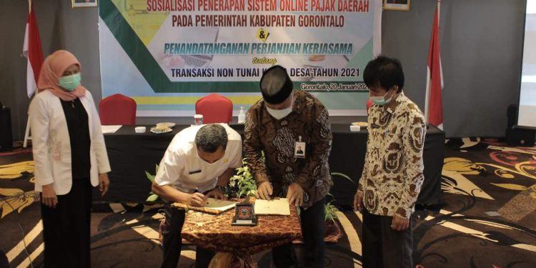 Penandatanganan Perjanjian Kerjasama yang diwakili oleh Kepala Dinas Pemerintah Desa Nawir Tondako Dan General Meneger Bank Sulut Go Cabang Limboto Yusuf Husain. (Putra/Gopos).