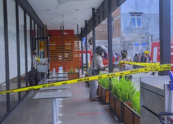 KEBAKARAN - Petugas Kepolisian memasang garis Polisi di areal gedung McD Gorontalo, Rabu (24/2/2021). (ari/gopos)