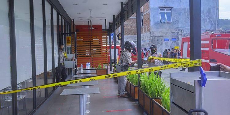 KEBAKARAN - Petugas Kepolisian memasang garis Polisi di areal gedung McD Gorontalo, Rabu (24/2/2021). (ari/gopos)