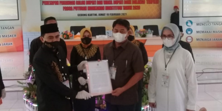 PENETAPAN PEMENANG - Komisi Pemilihan Umum (KPU) Bone Bolango menyerahkan SK penetapan Pemenang Pilkada 2020 kepada pasangan Hamim Pou-Merlan Uloli. (Indra/gopos)