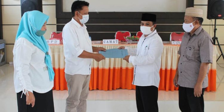KADES DULOHUPA - Prosesi penyerahan SK Jabatan PLT Kades Dulohupa oleh Sekretaris Kecamatan Telaga Romi Alulu Kepada PLT Kepala Desa Dulohupa Sukarno Danial Karim. (Putra/Gopos)