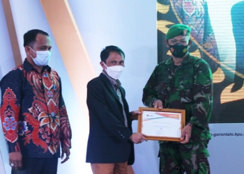 Bupati Gorontalo, Nelson Pomalingo (tengah), saat menyerahkan secara simbolis piagam penghargaan dari KPU Kabupaten  Gorontalo kepada Dandim 1314 Gorontalo Utara, di Balrom Maqna Hotel Kota Gorontalo, (Putra Gopos)