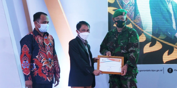 Bupati Gorontalo, Nelson Pomalingo (tengah), saat menyerahkan secara simbolis piagam penghargaan dari KPU Kabupaten  Gorontalo kepada Dandim 1314 Gorontalo Utara, di Balrom Maqna Hotel Kota Gorontalo, (Putra Gopos)