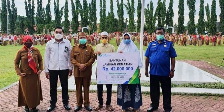 Sekda Boalemo, Sherman Moridu, didampingi Kepala BPJamsostek Cabang Pohuwato, Ady Syamsul, menyerahkan santunan JKM sebesar Rp42 juta kepada ahli waris almarhum Rifaldi Arief, petugas Non ASN Damkar Kabupaten Boalemo, pada saat apel kerja awal bulan, di Alun-Alun Kota, Tilamuta, Senin (1/3/2021). (Istimewa)