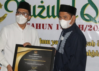 Kepala BPJS Ketenagakerjaan Cabang Gorontalo Hendra Elvian menyerahkan dua piagam penghargaan sekaligus kepada Bupati Bone Bolango Hamim Pou, disela peringatan Nuzulul Quran, di Masjid Agung Baitul Haq Islamic Center Bone Bolango, Rabu (28/4/2021) malam. (foto Irul/Kominfo)