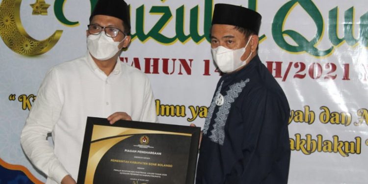 Kepala BPJS Ketenagakerjaan Cabang Gorontalo Hendra Elvian menyerahkan dua piagam penghargaan sekaligus kepada Bupati Bone Bolango Hamim Pou, disela peringatan Nuzulul Quran, di Masjid Agung Baitul Haq Islamic Center Bone Bolango, Rabu (28/4/2021) malam. (foto Irul/Kominfo)