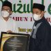 Kepala BPJS Ketenagakerjaan Cabang Gorontalo Hendra Elvian menyerahkan dua piagam penghargaan sekaligus kepada Bupati Bone Bolango Hamim Pou, disela peringatan Nuzulul Quran, di Masjid Agung Baitul Haq Islamic Center Bone Bolango, Rabu (28/4/2021) malam. (foto Irul/Kominfo)