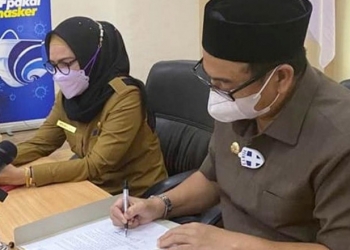 Bupati Hamim Pou didampingi Wakil Bupati Merlan S. Uloli menandatangani persetujuan pembayaran THR maupun gaji ke-14 bagi seluruh ASN di lingkungan Pemkab Bone Bolango, di ruang rapat Bupati Bone Bolango, Senin (3/5/2021). (foto Istimewa)