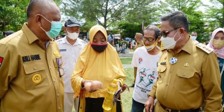 Gubernur Gorontalo Rusli Habibie bersama Wali Kota Gorontalo Marten Taha saat menyapa salah seorang masyarakat yang membeli di pasar murah yang kembali dilaksanakan oleh Pemprov Gorontalo khusus untuk maysarakat di Kota Tengah, Kota Gorontalo, Senin (10/5/2021). (Foto – Salman/Humas Pemprov)