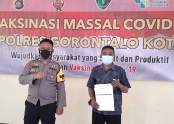 Salah seorang warga menunjukkan keterangan telah mengikuti vaksinasi Covid-19 dalam kegiatan vaksinasi massal oleh Polres Gorontalo Kota, Jumat (11/6/2021). (Dok. Humas Polda Gorontalo)
