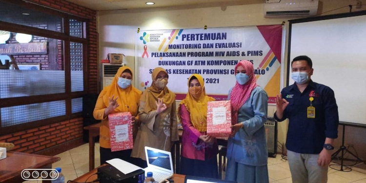 Kepala Dinas Kesehatan Provinsi Gorontalo, dr. Yana Yanti Suleman, sedang menyerahkan hadiah kepada petugas Puskesmas Dumbo Raya. Sebagai pemenang kategori layanan HIV dengan cakupan tes populasi kunci terbanyak, Rabu (3/6/2021). (Foto: Tim Infokom Dinkes)
