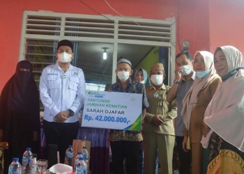 Bupati Bone Bolango Hamim Pou, saat menyerahkan santunan JKM BPJS Ketenagakerjaan kepada ahli waris dari almarhumah Sarah Djafar sebesar Rp42.000.000, pada acara doa arwah ke-40 hari atas meninggalnya almarhumah, di Desa Langge, Kecamatan Tapa. (Foto AKP/Kominfo)