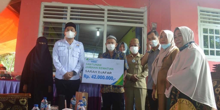 Bupati Bone Bolango Hamim Pou, saat menyerahkan santunan JKM BPJS Ketenagakerjaan kepada ahli waris dari almarhumah Sarah Djafar sebesar Rp42.000.000, pada acara doa arwah ke-40 hari atas meninggalnya almarhumah, di Desa Langge, Kecamatan Tapa. (Foto AKP/Kominfo)