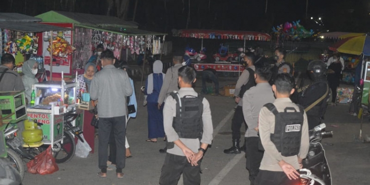 Pihak kepolisian saat memberikan himbauan kepada masyarakat dan pedagang di bawah Menara Keagungan Limboto untuk membubarkan diri karena adanya aturan PPKM, Sabtu (10/7/2021). Foto : Putra/Gopos