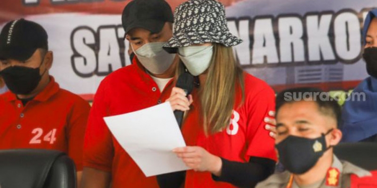 Ardie Bakrie menguatkan istrinya, Nia Ramadhani ketika menyampaikan permintaan maaf di hadapan awak media saat rilis kasus narkoba yang menjeratnya di Polres Metro Jakarta Pusat, Sabtu (10/7/2021). [Suara.com/Alfian Winanto]