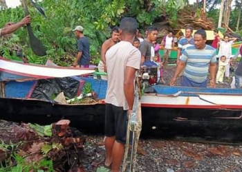 Warga Desa Sogitia mengevakuasi perahu yang rusak akibat tertimpa pohon yang tumbang, Kamis (15/7/2021). (istimewa)