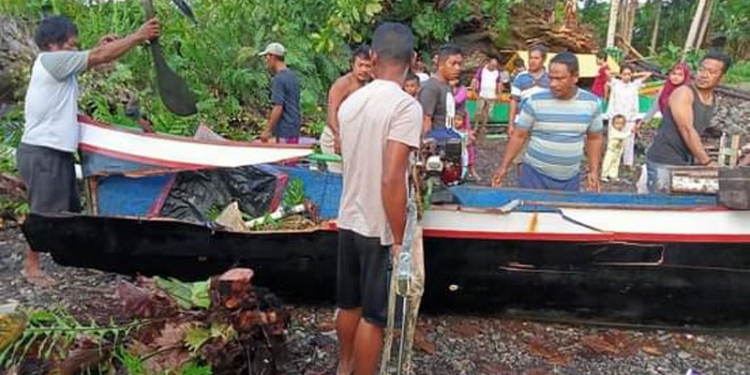 Warga Desa Sogitia mengevakuasi perahu yang rusak akibat tertimpa pohon yang tumbang, Kamis (15/7/2021). (istimewa)