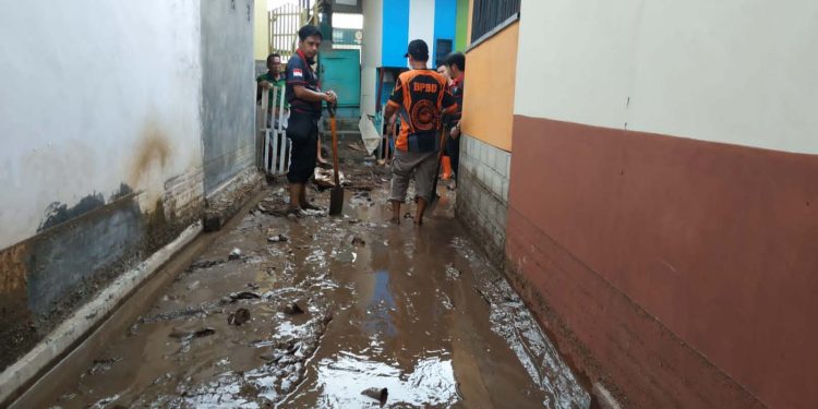 Tim BPBD Bone Bolango bersama pihak terkait saat membersihkan sisa lumpur akibat banjir yang menerjang Desa Huangobotu Kecamatan Kabila Bone. (Foto Istimewa)