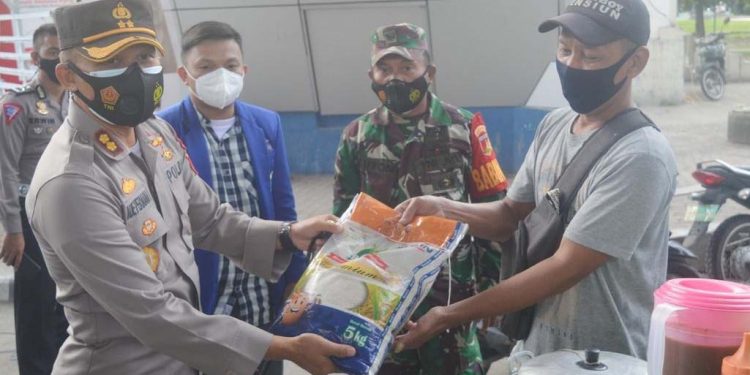 Kapolres Gorontalo, AKBP Ade Permana saat memberikan bantuan beras kepada salah satu Pedagang Kaki Lima (PKL) di Kawasan Menara Limboto, Jumat (23/7/2021). (Foto: Putra/Gopos)