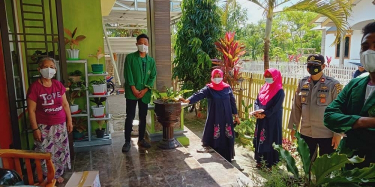 Kapolsek Limboto IPTU Arpaing Ami dibantu beberapa mahasiswa saat memberikan bantuan kepada masyarakat terdampak Covid-19, di Kecamatan Limboto. (Foto: Putra/Gopos)