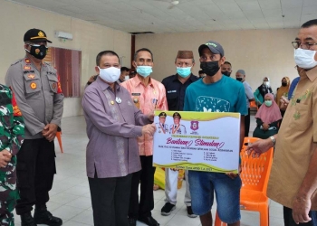 Wagub Gorontalo H. Idris Rahim, menyerahkan secara simbolis bantuan stimulan bagi korban bencana kebakaran pada bakti sosial NKRI Peduli di Kecamatan Tibawa, Kabupaten Gorontalo, Kamis (29/7/2021). (Foto: Haris/Kominfo)