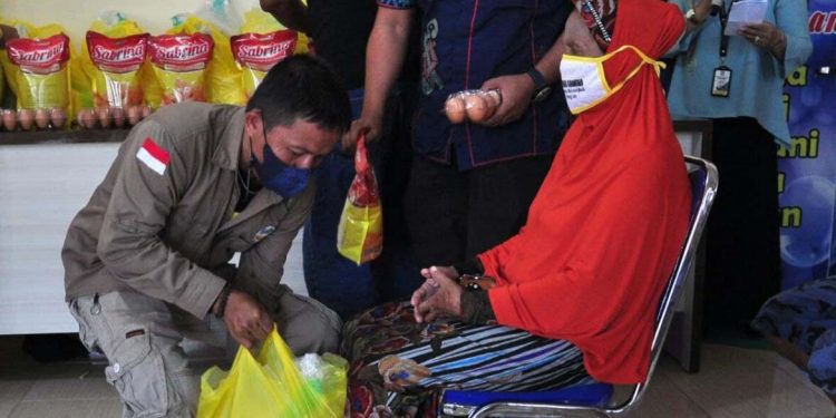 Petugas dari Dinas Sosial Provinsi Gorontalo (kiri), menyerahkan paket bantuan langsung pangan kepada Keluarga Penerima Manfaat (KPM) pada bakti sosial NKRI Peduli di Kecamatan Pulubala, Kabupaten Gorontalo, Kamis (29/7/2021). (Foto: Haris/Kominfo)