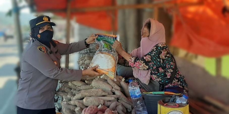 Kapolsek Dungigi, IPDA Pranti Natalia Olii, saat membagikan bantuan beras kepada masyarakat terdampak PPKM level 3. (Foto: Putra/Gopos)