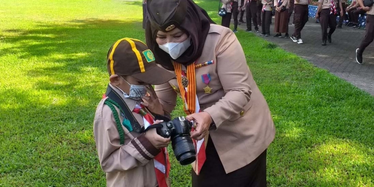 Ketua Kwartir Daerah (Kwarda) Gerakan Pramuka Gorontalo, Idah Syahidah saat melihat hasil foto dari fotografer muda yang merupakan anggota pramuka Sekolah Dasar Islam Terpadu Lukmanul Hakim Limboto, Damar Pandu Raazzaq Usman . (Foto: Indra/Gopos)