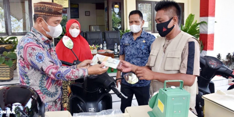 Bupati Pohuwato, Saipul Mbuinga (kiri) menyerahkan Surat Tanda Nomor Kendaraan (STNK) dalam penyerahan sepeda motor cool box bagi penjual ikan keliling, Jumat (20/8/2021)