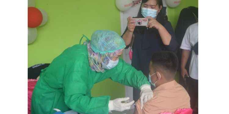 Cristian Ginting (13) siswa yang duduk dibangku kelas VIII bersama ibunya saat melaksanakan vaksinasi Covid-19 di SMP Negeri 1 Telaga Biru, Rabu (25/8/2021) Foto : Putra/Gopos.