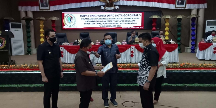 Marten A. Taha, Walikota Gorontalo sedang menyerahkan rancangan Perubahan APBD kota Gorontalo tahun anggaran 2021, kepada Hardi Sidiki, Ketua Dewan Perwakilan Rakyat Daerah (DPRD) Kota Gorontalo, Rabu (18/8/2021). (Foto: Sari/gopos)