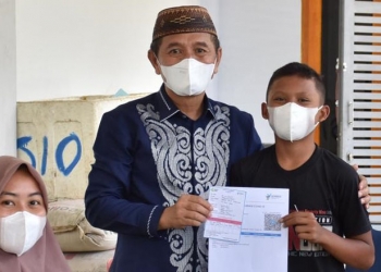 Bupati Pohuwato, Saipul Mbuinga (karawo biru) menyerahkan surat tanda vaksin bagi anak yang mengikui vaksinasi di kompleks Pasar Marisa, Pohuwato. (istimewa)