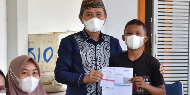 Bupati Pohuwato, Saipul Mbuinga (karawo biru) menyerahkan surat tanda vaksin bagi anak yang mengikui vaksinasi di kompleks Pasar Marisa, Pohuwato. (istimewa)