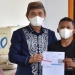 Bupati Pohuwato, Saipul Mbuinga (karawo biru) menyerahkan surat tanda vaksin bagi anak yang mengikui vaksinasi di kompleks Pasar Marisa, Pohuwato. (istimewa)
